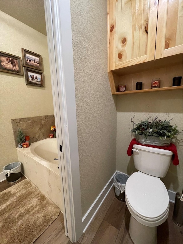 bathroom with hardwood / wood-style flooring, toilet, and a bathing tub