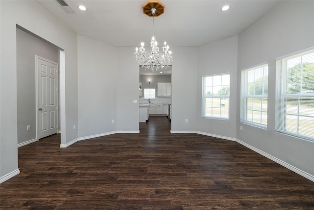 unfurnished dining area with dark wood-type flooring and an inviting chandelier