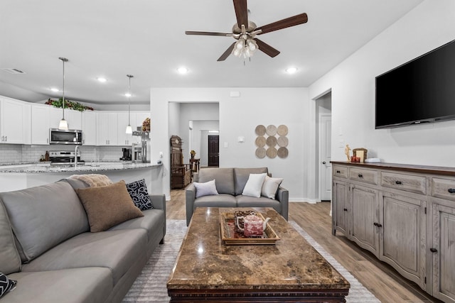 living room featuring ceiling fan and light hardwood / wood-style flooring