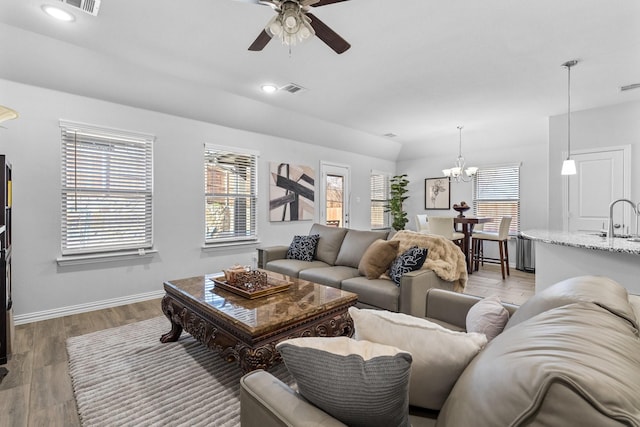 living room with sink, ceiling fan with notable chandelier, and light wood-type flooring