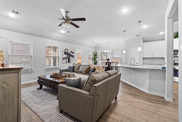 living room with sink, ceiling fan with notable chandelier, and light hardwood / wood-style flooring