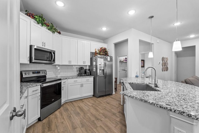 kitchen featuring sink, pendant lighting, stainless steel appliances, washer / clothes dryer, and white cabinets