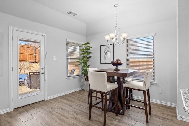 dining area featuring vaulted ceiling, light hardwood / wood-style floors, and a chandelier