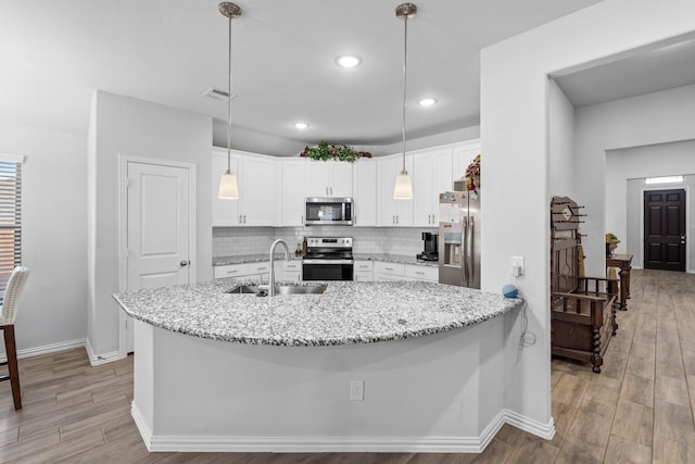 kitchen with sink, white cabinetry, stainless steel appliances, tasteful backsplash, and decorative light fixtures