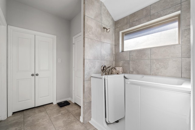 bathroom featuring a washtub, tile patterned floors, and tile walls