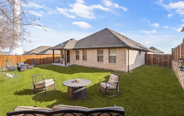 rear view of house with a yard and an outdoor fire pit