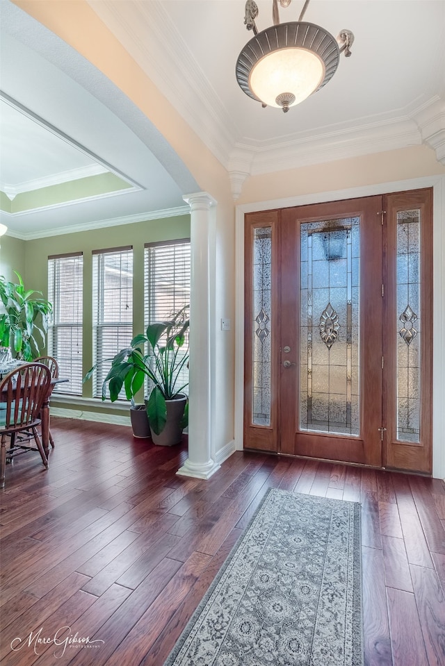 entrance foyer featuring ornate columns, a raised ceiling, ornamental molding, and dark hardwood / wood-style flooring