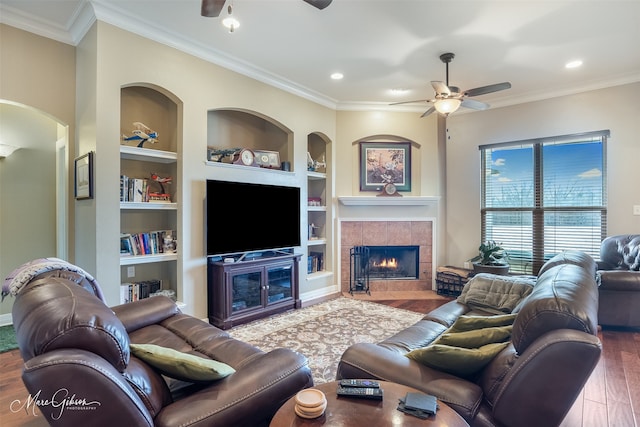 living room with crown molding, hardwood / wood-style floors, built in shelves, and ceiling fan