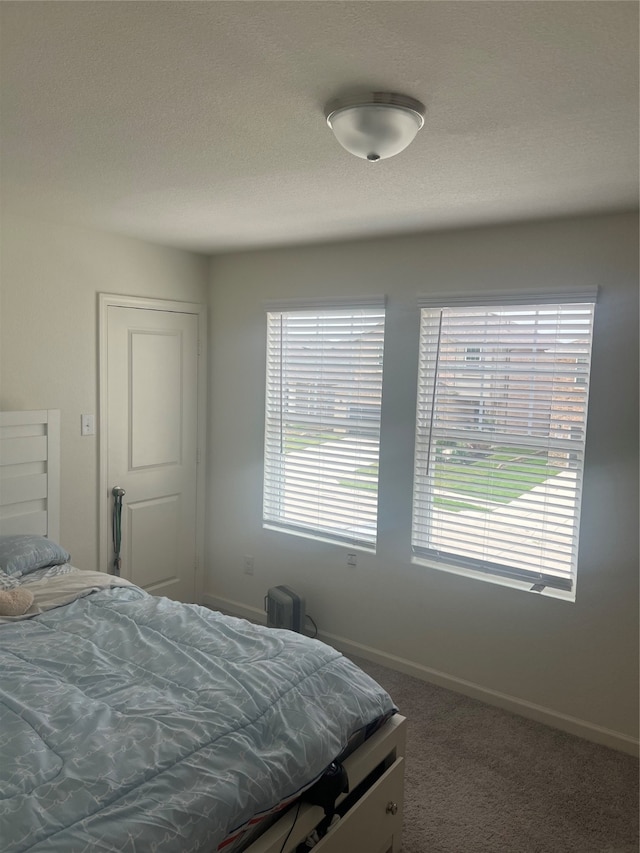 bedroom featuring a textured ceiling and dark colored carpet