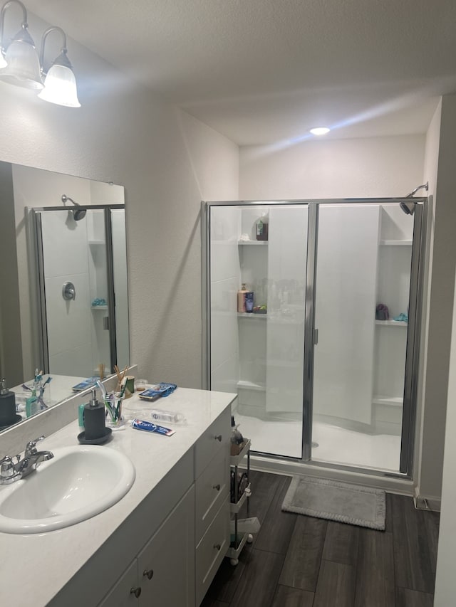 bathroom with vanity, a shower with door, hardwood / wood-style floors, and a textured ceiling