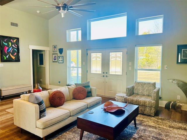 living room featuring a high ceiling, wood finished floors, visible vents, baseboards, and french doors