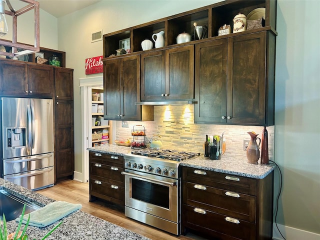 kitchen with light stone counters, stainless steel appliances, visible vents, backsplash, and open shelves