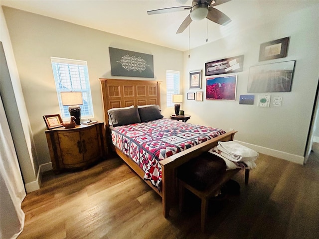 bedroom with ceiling fan, wood finished floors, and baseboards