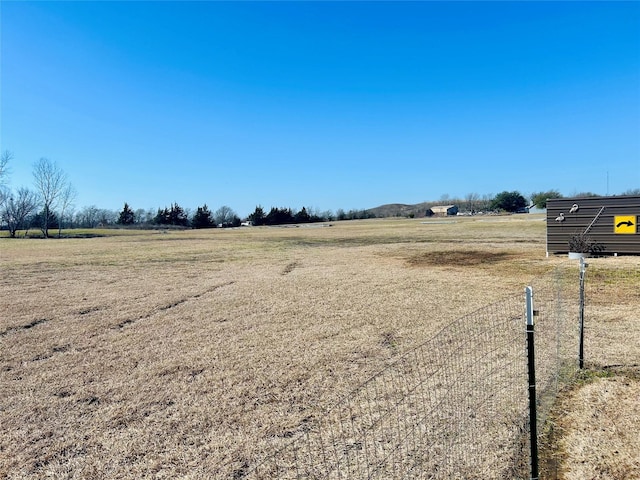 view of yard with fence and a rural view