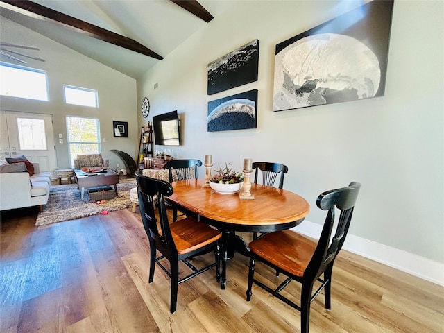 dining room with high vaulted ceiling, beam ceiling, and light hardwood / wood-style floors