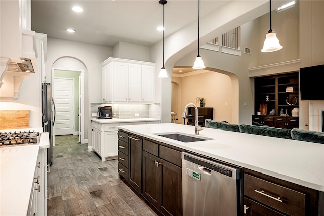 kitchen with appliances with stainless steel finishes, pendant lighting, sink, backsplash, and dark brown cabinetry