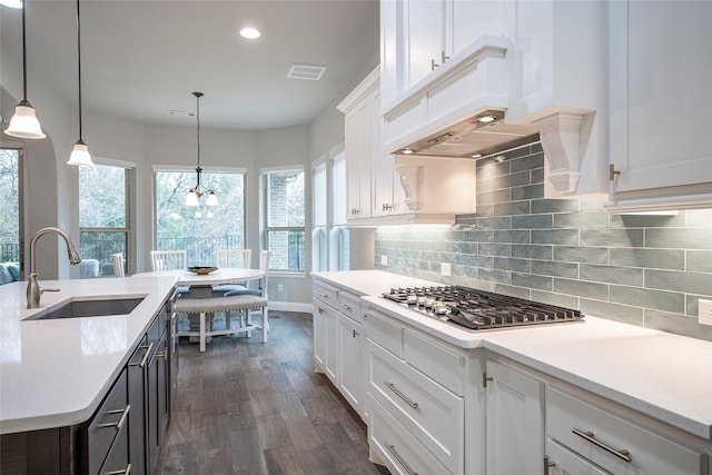 kitchen featuring pendant lighting, tasteful backsplash, sink, white cabinets, and stainless steel gas cooktop