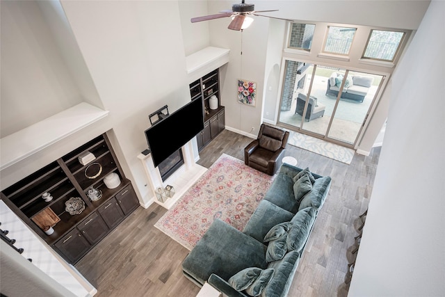 living room with hardwood / wood-style flooring, ceiling fan, and a high ceiling