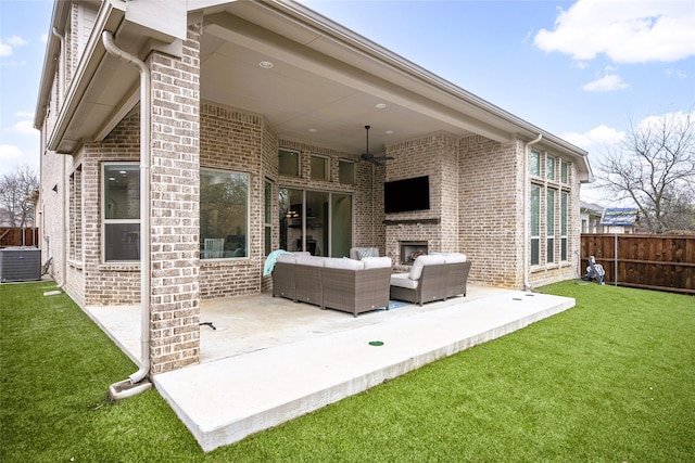 back of house featuring an outdoor living space with a fireplace, a yard, central AC unit, and a patio area