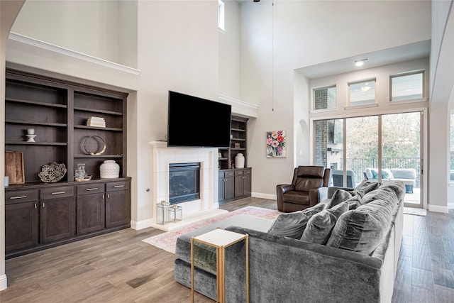 living room with a fireplace, light hardwood / wood-style floors, and a high ceiling