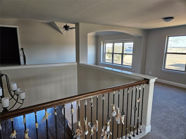 stairs with ceiling fan, carpet, and a textured ceiling