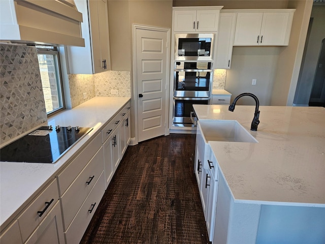 kitchen featuring white cabinetry, appliances with stainless steel finishes, light stone counters, and wall chimney exhaust hood