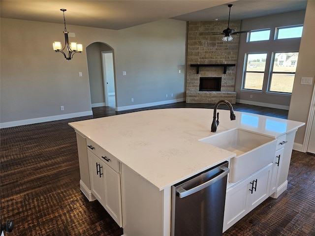 kitchen with white cabinetry, decorative light fixtures, stainless steel dishwasher, and a center island with sink