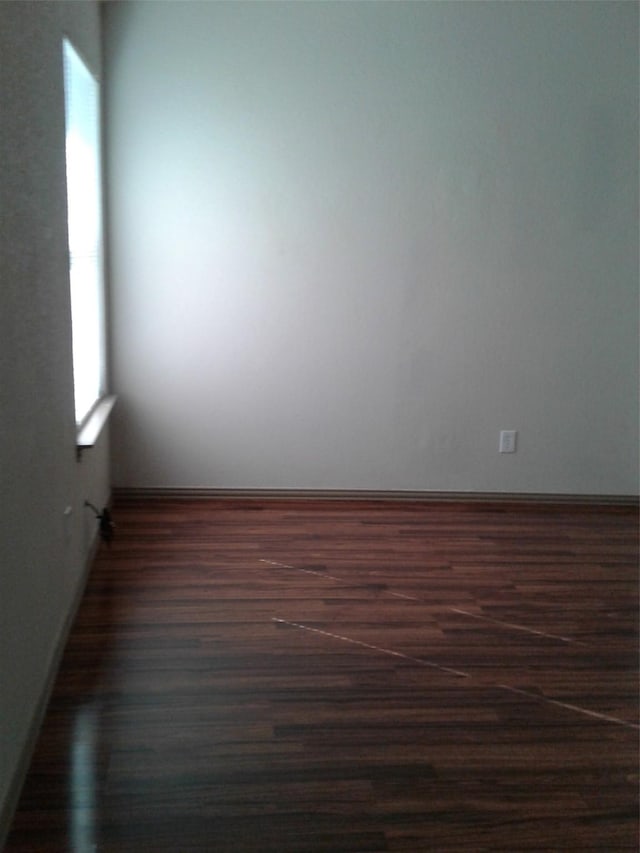 spare room featuring a healthy amount of sunlight and dark wood-type flooring