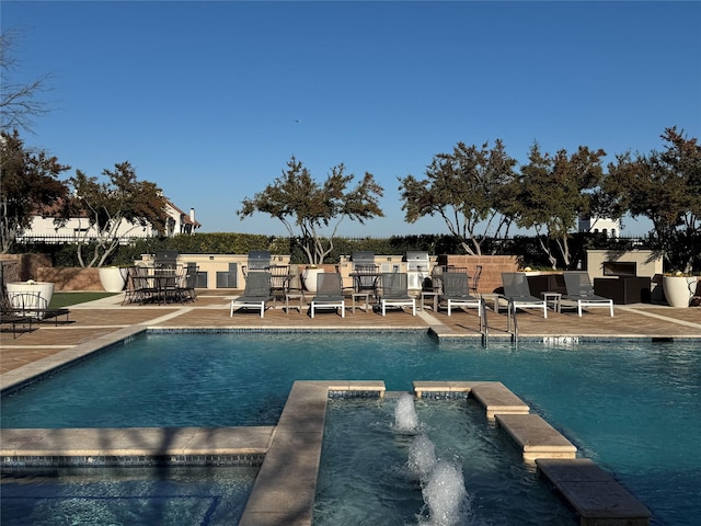 view of pool featuring a patio area, pool water feature, and an in ground hot tub