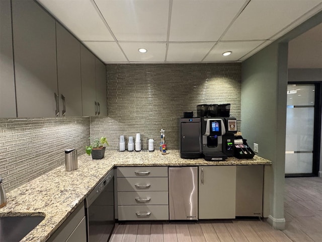 kitchen with light stone counters, fridge, gray cabinets, black dishwasher, and decorative backsplash