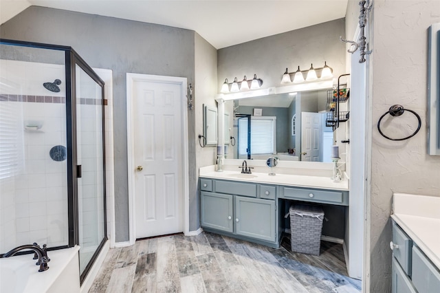 full bathroom featuring a textured wall, wood finished floors, vanity, a shower stall, and a bath