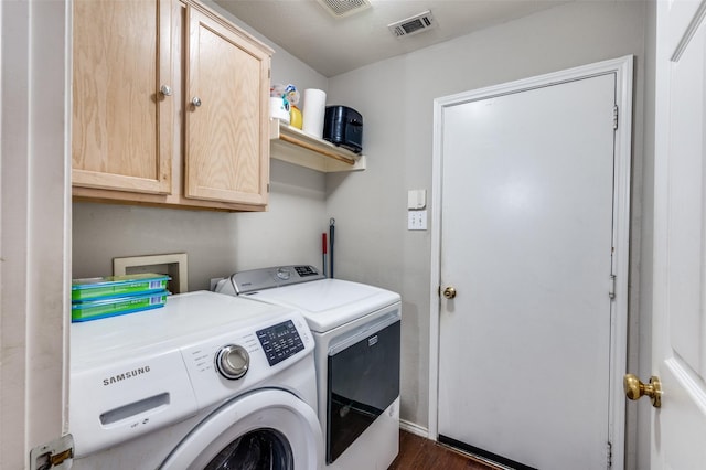 laundry room with washing machine and dryer, cabinet space, and visible vents