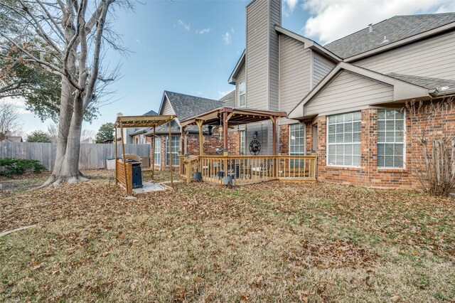 rear view of house with brick siding, fence, a yard, roof with shingles, and a chimney