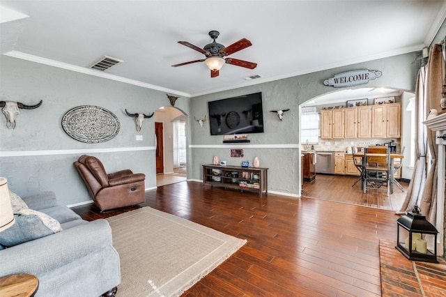 living room with arched walkways, a textured wall, dark wood finished floors, and a wealth of natural light