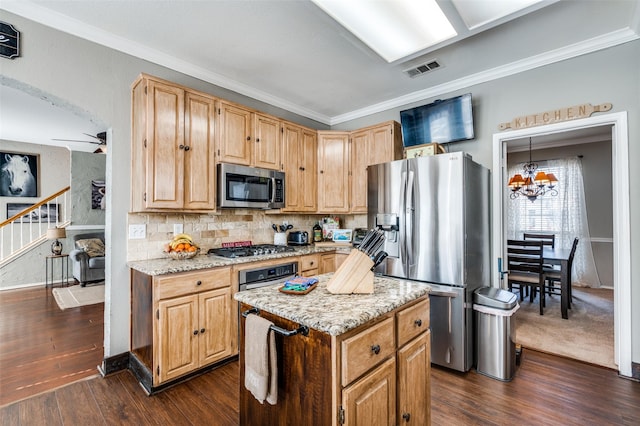 kitchen with decorative backsplash, a kitchen island, appliances with stainless steel finishes, ornamental molding, and dark wood-type flooring