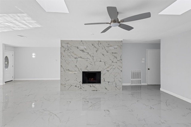 3521 Post Oak Rd, Garland, TX 75044 - unfurnished living room featuring marble tiled flooring, baseboards, a skylight, a high end fireplace, and a ceiling fan