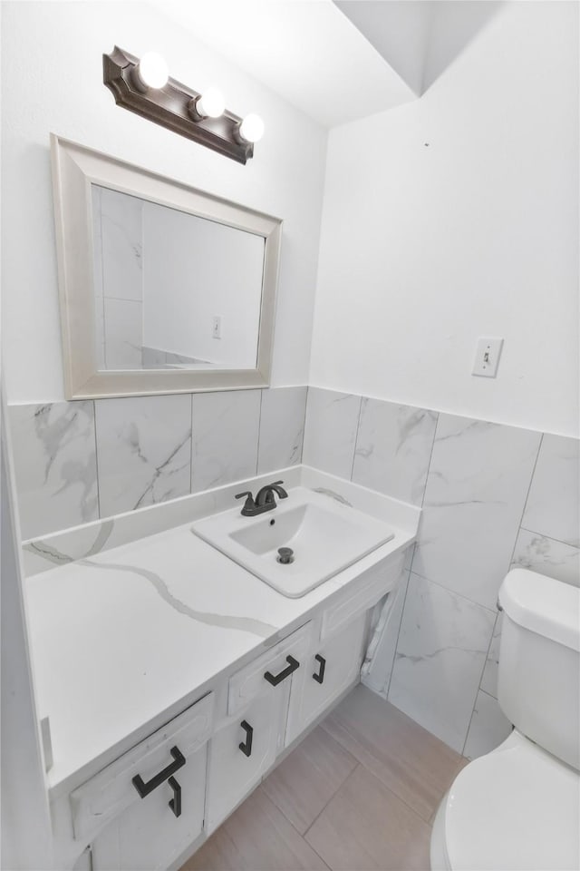 bathroom featuring vanity, toilet, and tile walls