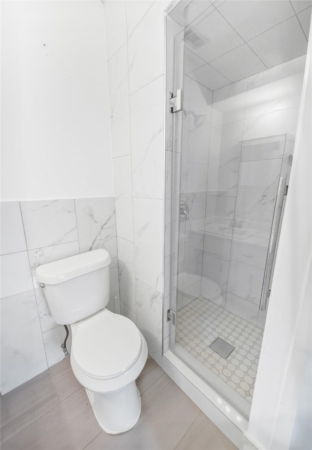 bathroom featuring toilet, tile walls, and a tile shower