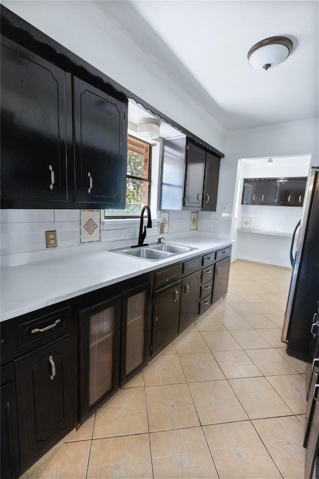 kitchen with tasteful backsplash, ornamental molding, sink, and light tile patterned floors