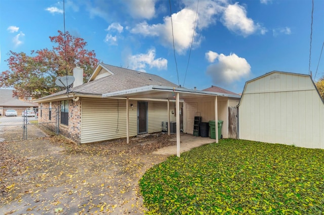 back of house featuring a carport and a storage shed