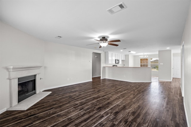 unfurnished living room featuring dark hardwood / wood-style flooring and ceiling fan with notable chandelier