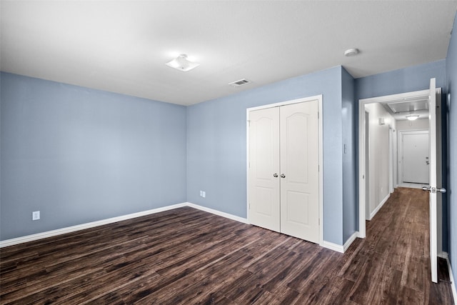 unfurnished bedroom with dark wood-type flooring and a closet