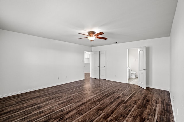 unfurnished bedroom featuring dark wood-type flooring, ensuite bath, ceiling fan, and a closet