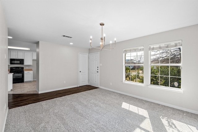 unfurnished room with an inviting chandelier and light colored carpet