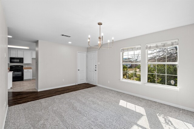 empty room with dark carpet and a chandelier