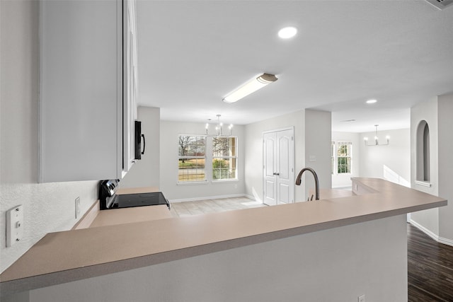 kitchen featuring dark wood-type flooring, sink, decorative light fixtures, a notable chandelier, and stove