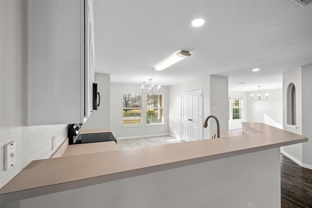 kitchen featuring sink, black appliances, kitchen peninsula, ceiling fan, and white cabinets