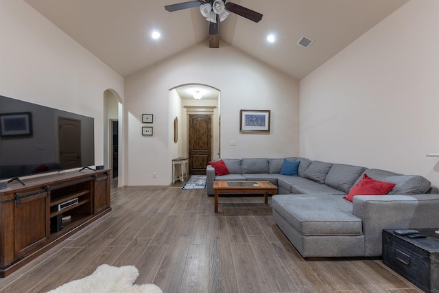 living room with ceiling fan, high vaulted ceiling, beamed ceiling, and light wood-type flooring