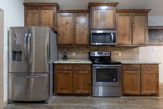 kitchen with light stone counters, stainless steel appliances, and decorative backsplash