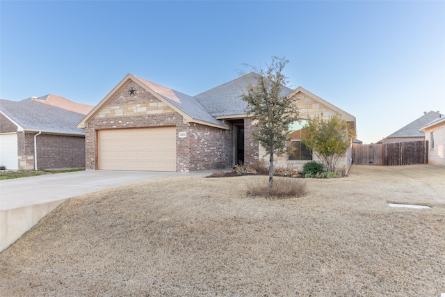 view of front of house featuring driveway, fence, a shingled roof, a garage, and brick siding